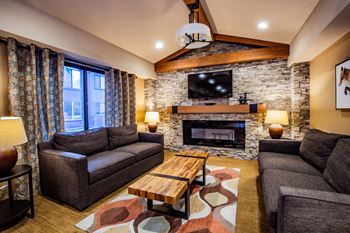 A living room with a stone fireplace and a flat screen TV mounted above it.